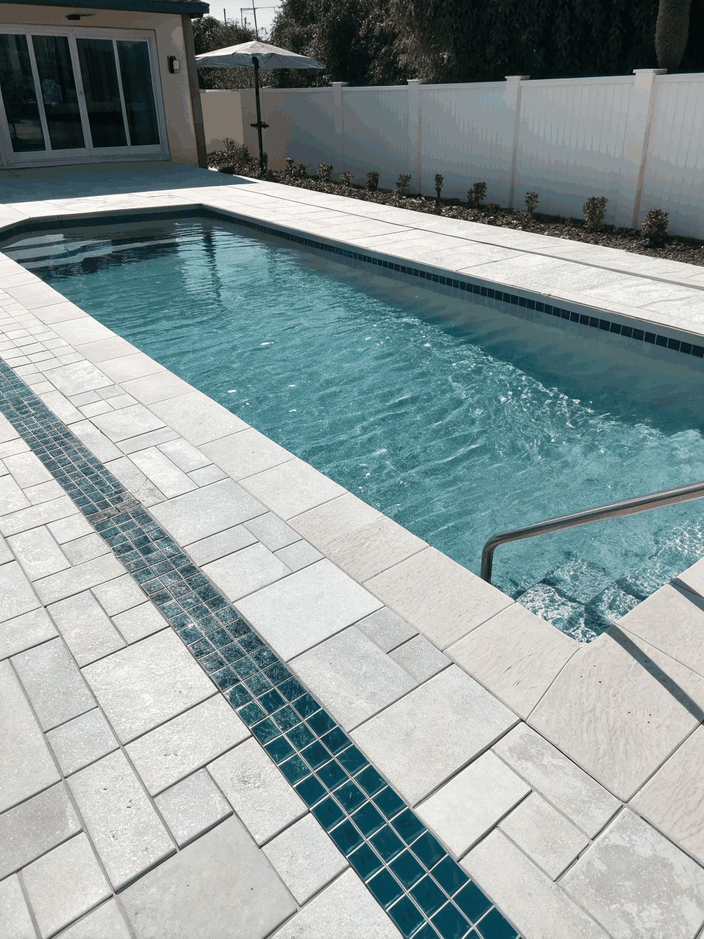 Completed pool renovation with travertine decking and a glass tile band, North Alabama
