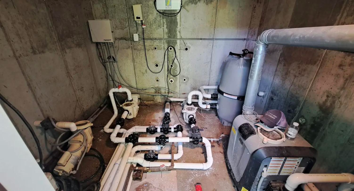 Before: neglected pool equipment vault with corroded plumbing and disorganized wiring