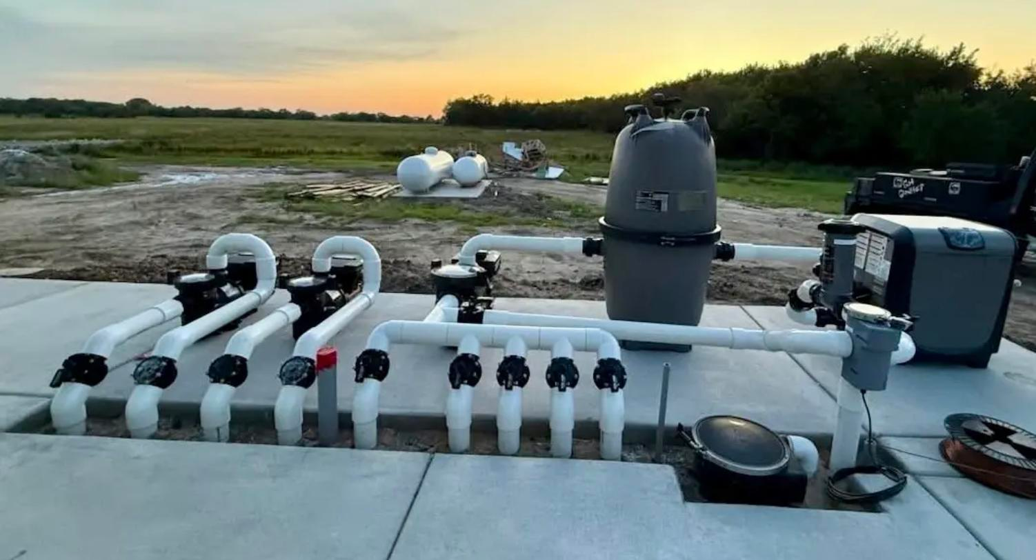 Engineered pool equipment pad with valve manifold, filter and heater at sunset