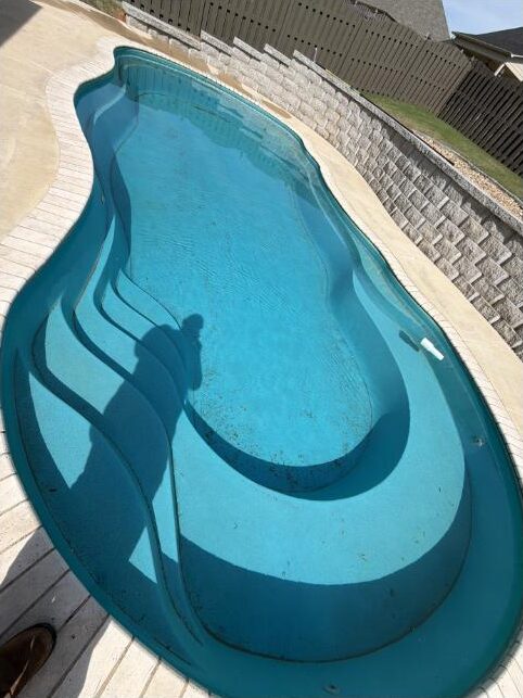 Renovated freeform pool with clear water, new surface and clean coping after completion