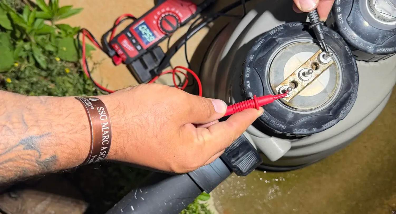 Technician using a multimeter to diagnose a pool light circuit at the equipment pad