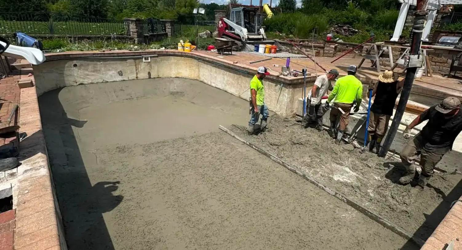 Crew placing and screeding shotcrete during a pool shell renovation